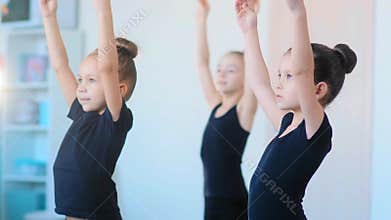 Young girls in tracksuits stretch hands standing in studio