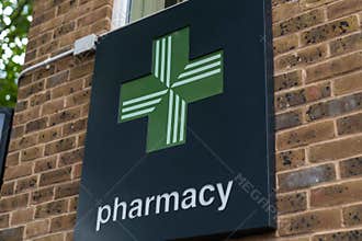 A close up shot of a a green cross Pharmacy logo sign