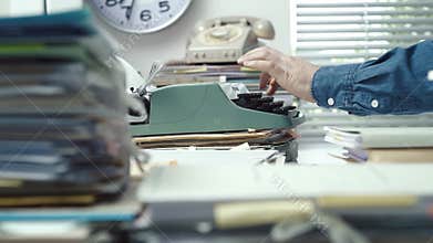 Employee typing with a typewriter and piles of paperwork
