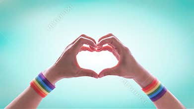 LGBT pride month with rainbow flag ribbon wristband on LGBTQ people heart-shape hands for International day against homophobia