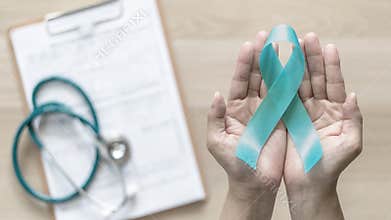 Teal ribbon awareness on woman`s hand for Ovarian Cancer, Polycystic Ovary Syndrome PCOS disease, Post Traumatic Stress Disorder