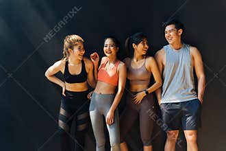 Happy smiling man and women having fun talking in gym. Group of young people relaxing in gym after workout training.