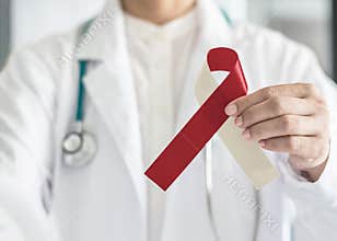 Burgundy ivory ribbon awareness on doctor’s hand, symbolic bow color for head and neck cancer, oral squamous cell carcinoma