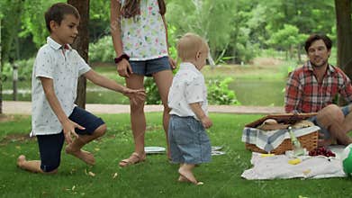 Happy siblings playing in park. Young family having picnic outdoors.