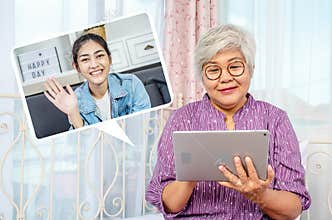 Portrait of smiling senior woman with eyeglasses using electronic tablet for conversation with daughter via video chat