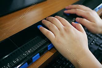 Close-up blind person hands using computer with braille display or braille terminal a technology assistive device for persons with
