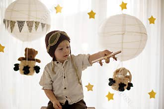 Sweet toddler boy, playing with airplane and teddy bear, air balloons with toys behind him