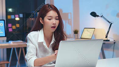 Young Asian business woman on video conference call, using laptop computer work late night. Remote meeting, work at home concept