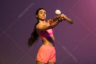 African american girl in pink sports bra playing baseball on purple background