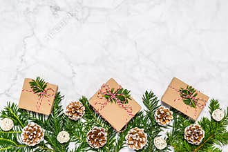 Plastic free Christmas flat lay with conifer tree branches, pine cones and handmade giftboxes on marble background. Greeting card
