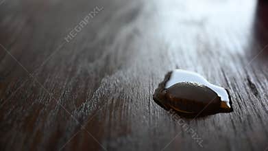 Slow melting of an ice cube on a wooden table while back lit