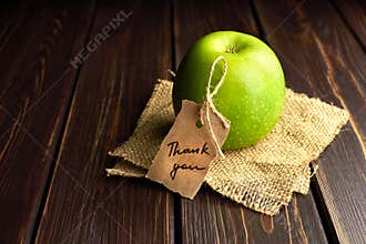 Green apple gift with thank you lable on dark wooden table background. Teachers day