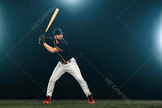 Baseball player with bat on dark background. Ballplayer portrait.