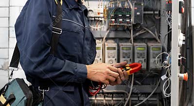 Electrician engineer checks electrical circuit in control panel for high current and voltage, starting and commissioning