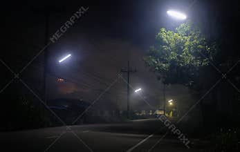 Empty road underneath street light with smoke at night and UFO on background
