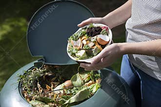 Close Up Of Woman Emptying Food Waste Into Garden Composter At Home
