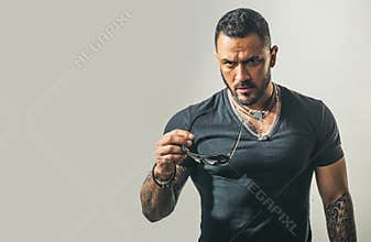 Handsome sexy confident man in sunglasses. Serious guy posing in studio. Mens sexuality or attraction and charisma.