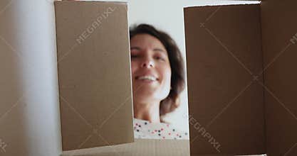 Woman opens parcel looks at delivered goods feels happy