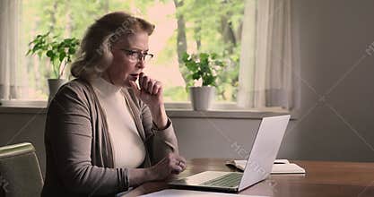Elderly woman using laptop experiences problems with device feels angry