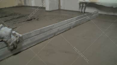 Worker screeding sand bedding to level for laying granite paver blocks. Laying gray concrete paving slabs in house