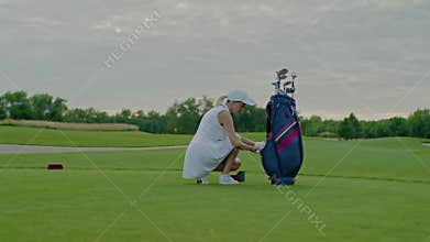 Athlete Woman Takes Ball Out of Golf Bag.