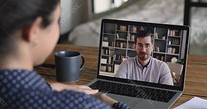 Laptop screen view over female shoulder talking using videocall app