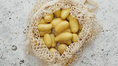 Young fresh Potatoes in a ecological zero-waste net bag placed on white scratched background