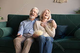 Excited mature couple laughing while watching comedy movie.