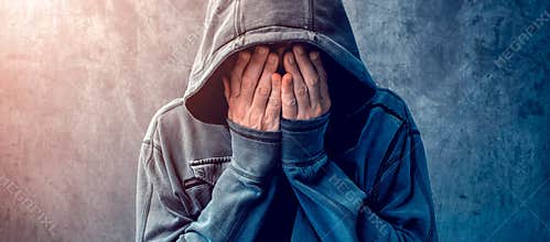 Desperate man in hooded jacket is crying