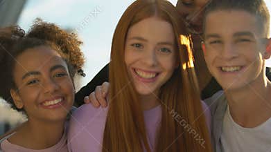 Joyful teenagers hugging female friend smiling on camera, adolescent wellness