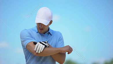 Upset male golfer feeling pain in elbow, touching aching area, sports trauma