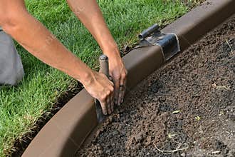 Concrete curb edging being shaped for smoothness in a flower bed