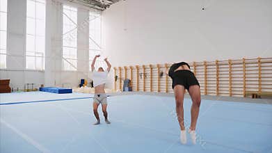 Two sportsman doing a cartwheel and a double back flip, steadicam, slow motion.