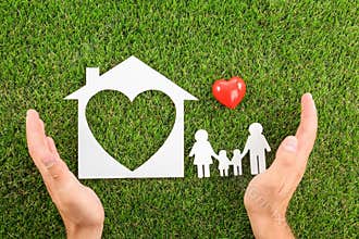 Man holding hands near figures of house, heart and family on green grass