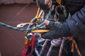 Male rope access worker dressing with industry fall protection yellow helmet abseiling safety body harness prior to work