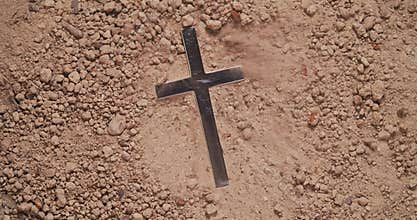 Blowing away dirt to discover hidden metal cross
