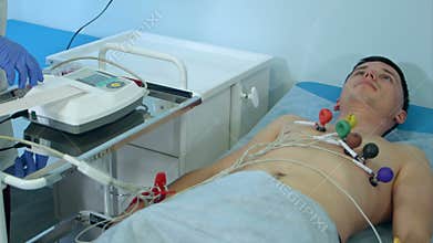 Nurse with ECG equipment making cardiogram test to male patient in hospital clinic