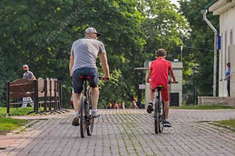 Father and his son riding bicycles in the park, back side view.