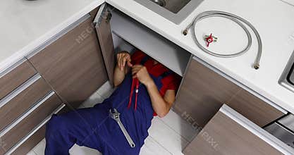 Plumbing services - plumber working in domestic kitchen