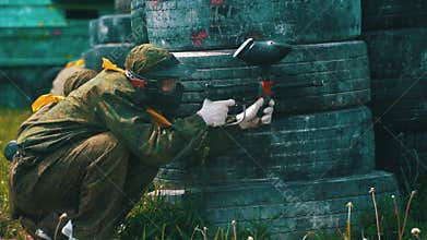 Guy in camouflage with mask shoots with paintball gun