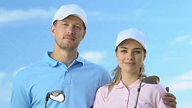 Confident male and female golfers posing with clubs, trainers of golf school