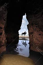 Horse galloping past cave