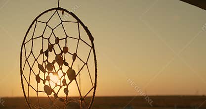 Native American dreamcatcher hanging in breeze at sunset.