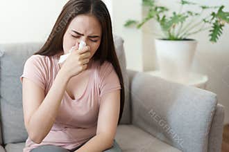 Asian Cute of  girl having  flu season and sneeze using paper tissues sitting on sofa at home, Health and illness concepts