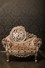 Vintage chair with gold accents beside the wall