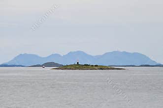 Small lighthouse on an islet of Vega archipelago in Norwegian sea against the background of Gullsvågfjellet Mountain