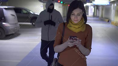 Robber in a balaclava and a young woman victim in a parking car