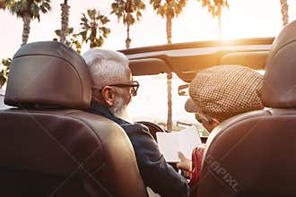 Happy senior couple having fun on new convertible car - Mature people enjoying time together during road trip vacation