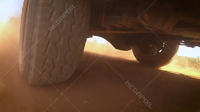 Rear wheel of 4x4 4WD off road SUV pickup truck driving on the dirty ground, off road travel in the local road with dusk for adven
