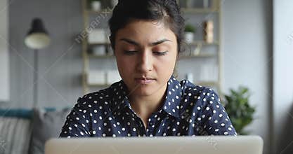 Thoughtful concerned indian woman working on computer thinking solving problem